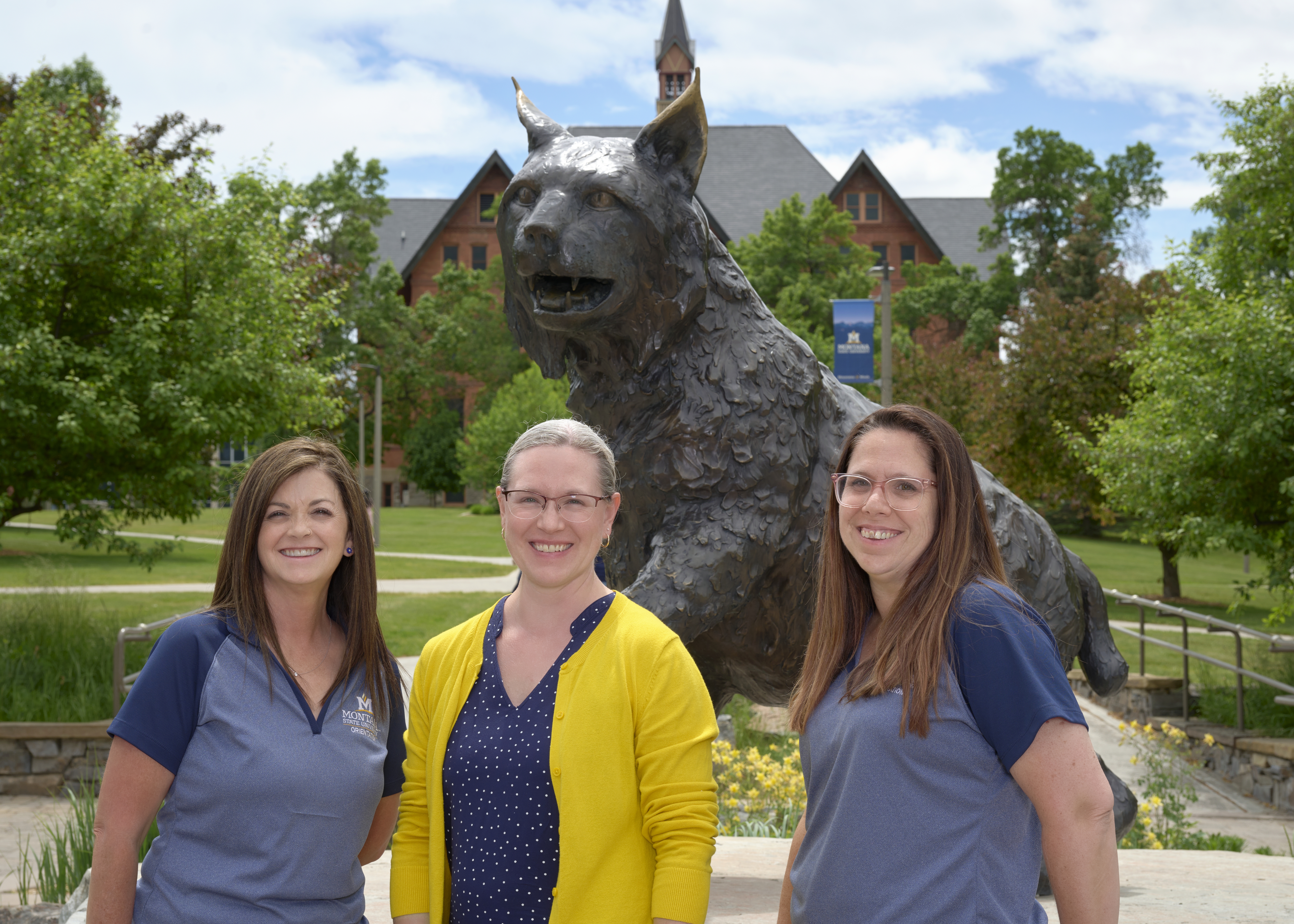 three ladies smiling outside in front of the Spirit statue