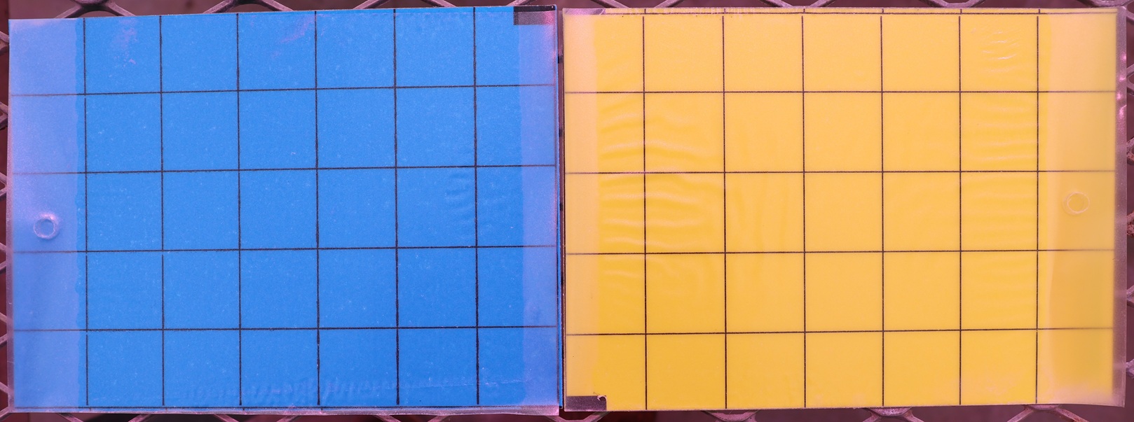 A photo of two rectangular cards, one blue and one yellow, with black grids on them